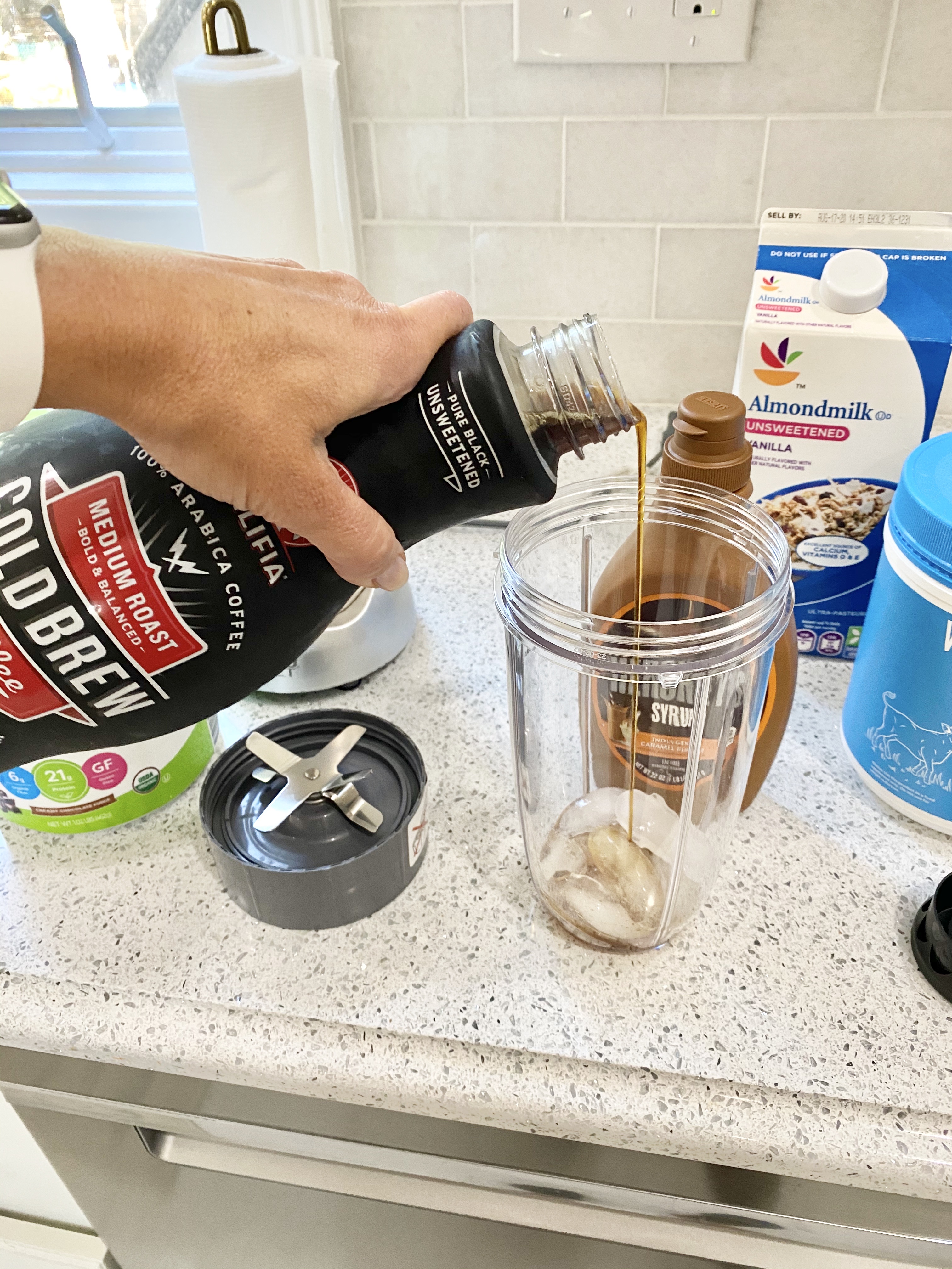 person pouring cold brew to make Caramel Chocolate Protein Iced Coffee