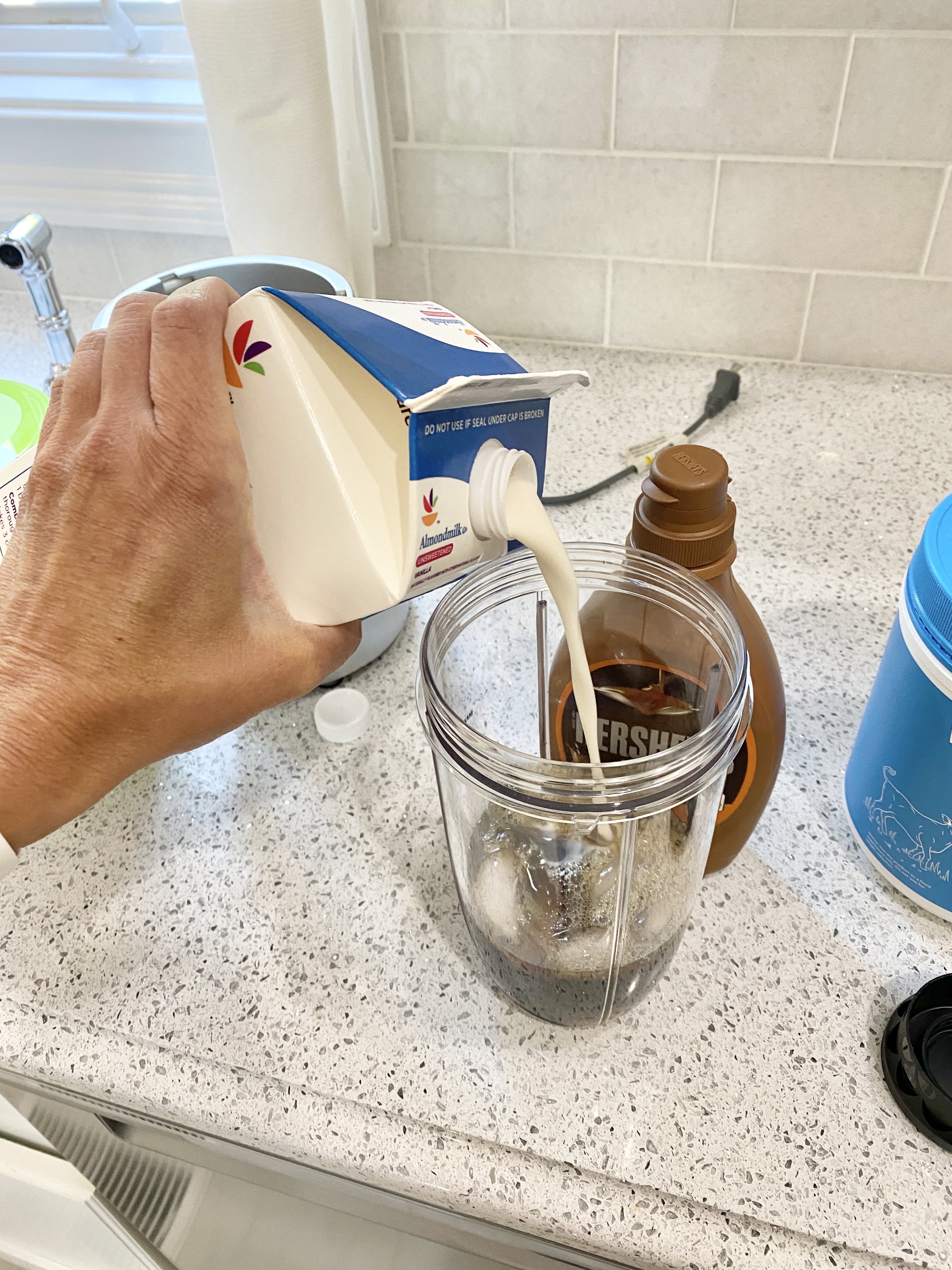 person adding milk to a blender